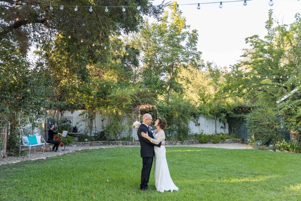bride and groom standing on the lawn at the Lavender Inn in Ojai with a cellist playing during their intimate elopement