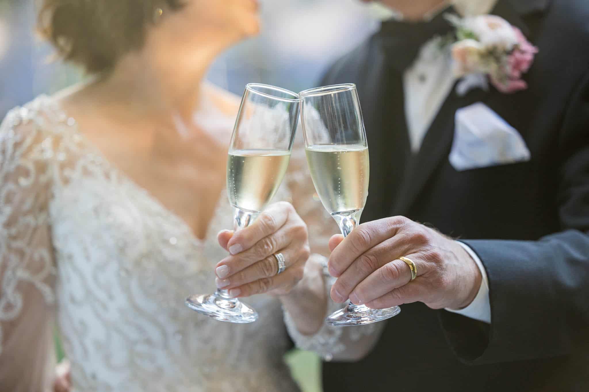 bride and groom toasting their champagne glasses together while looking at each other and smiling