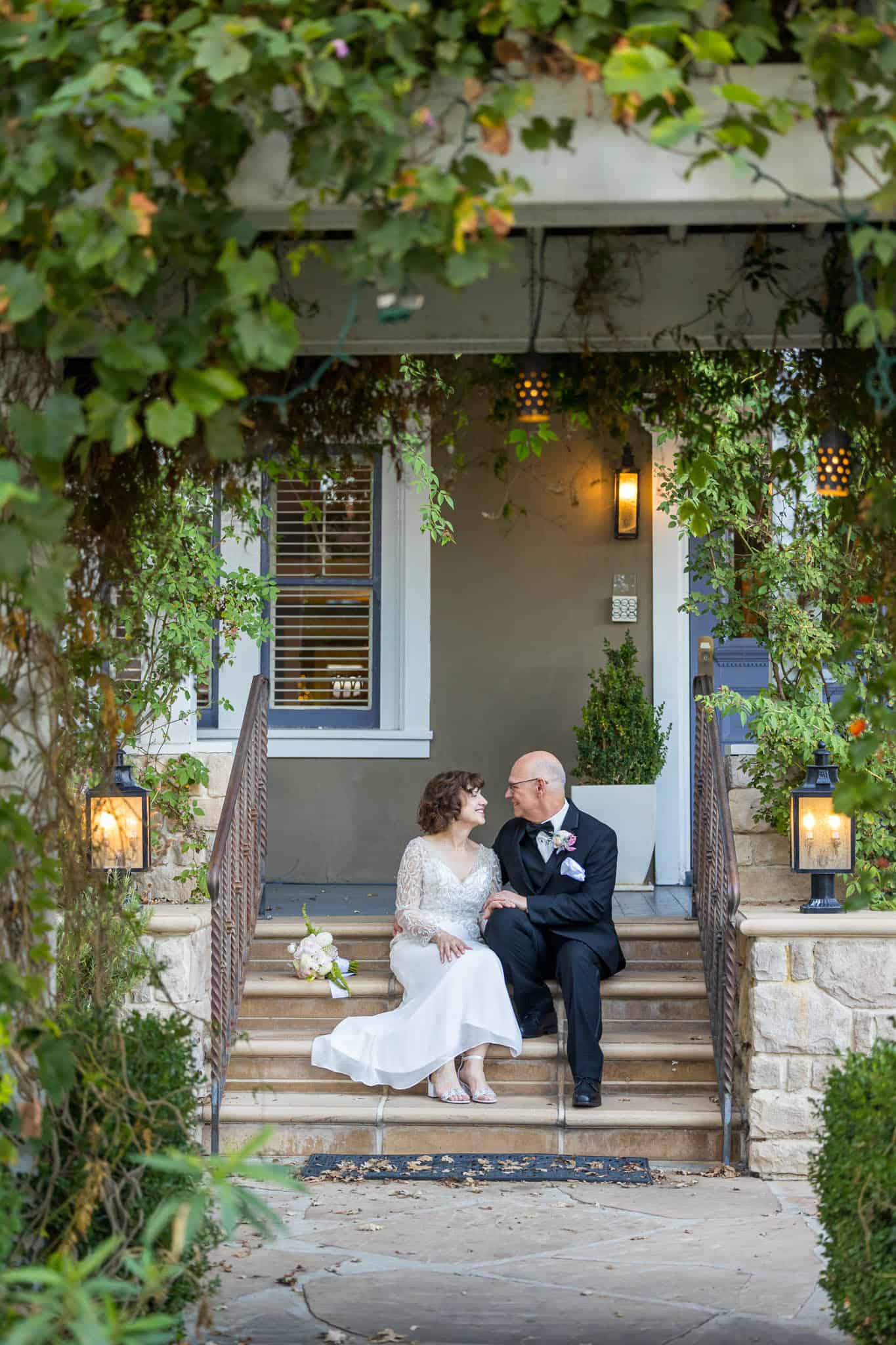 bride and groom sitting on the stairs of Lavender Inn in Oaji photographed by Ventura County wedding photographer