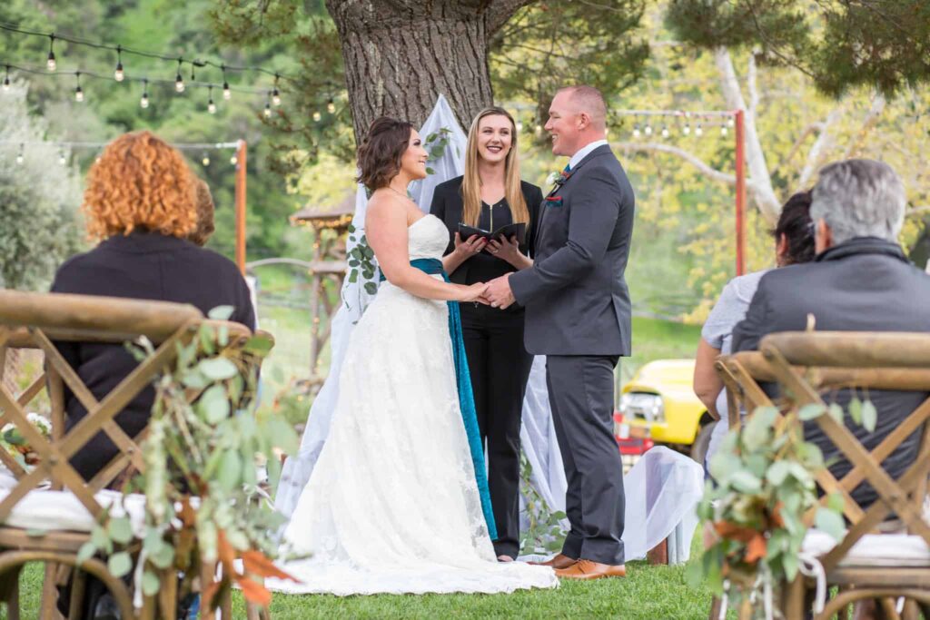 bride and groom holding hands at the alter for their outdoor wedding ceremony at the Old Creek Ranch Winery with Ventura County wedding photographer