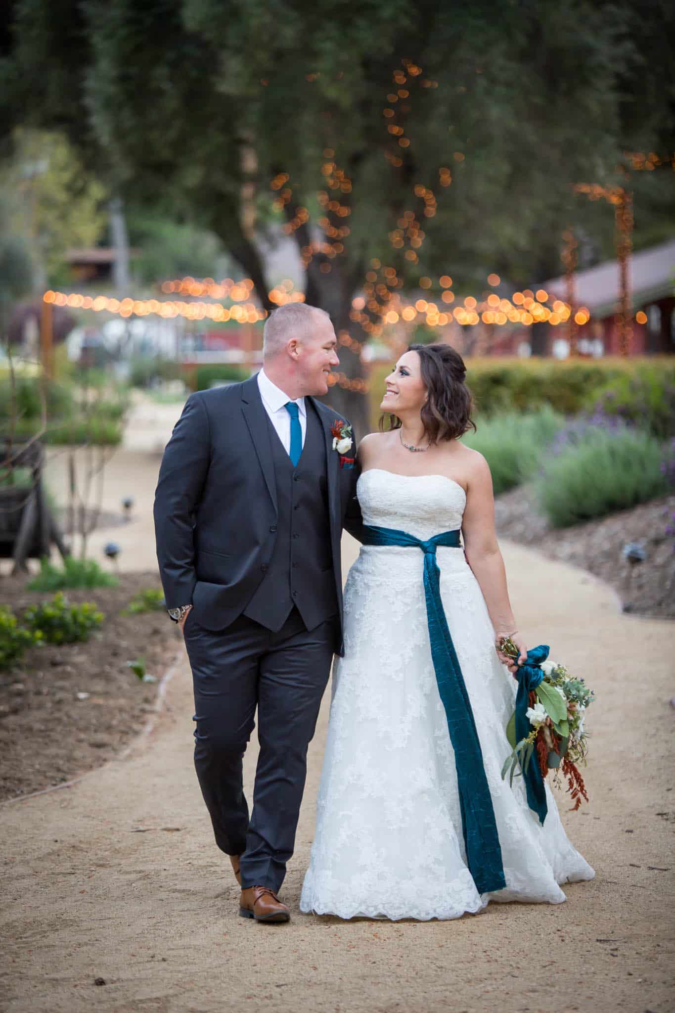 bride and groom walking together down a path and smiling at one another for their bridal portraits with Ventura wedding photographer at Old Creek Ranch Winery