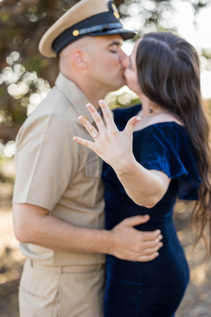 woman showing off her engagement ring while kissing her militart fiancé after he proposed to her in ventura