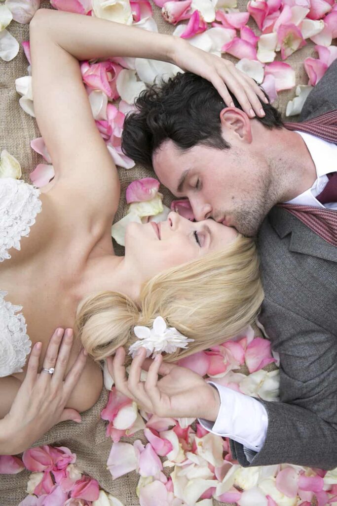 bride and groom laying on pink rose petals santa barbara wedding photograph