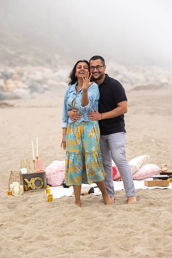 woman showing off her ring after fiancé proposed on beach in malibu