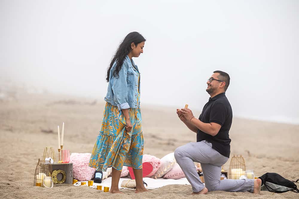 man proposing on the beach with a picnic
