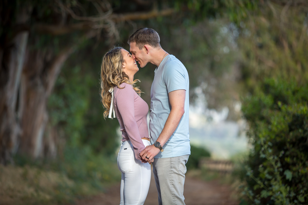couple laughing while kissing engagement session carpinteria bluffs